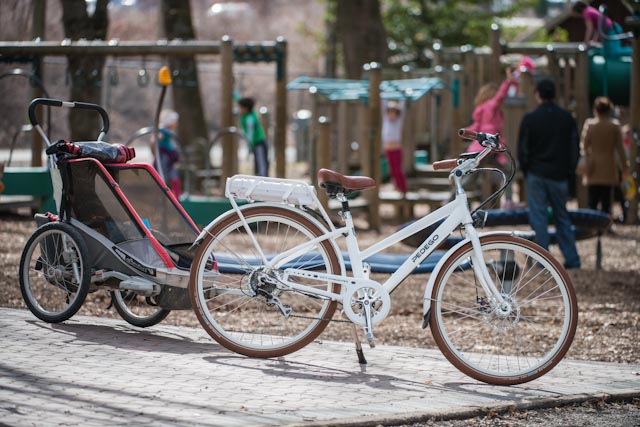 White Pedego electric bike with a passenger cargo carrier attached