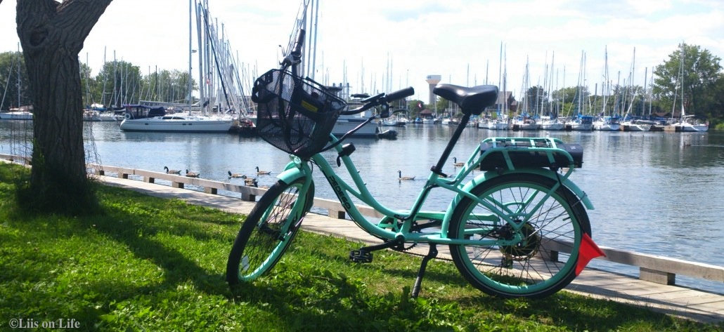 Seafoam coloured pedego sitting at the harbour next to sailboats
