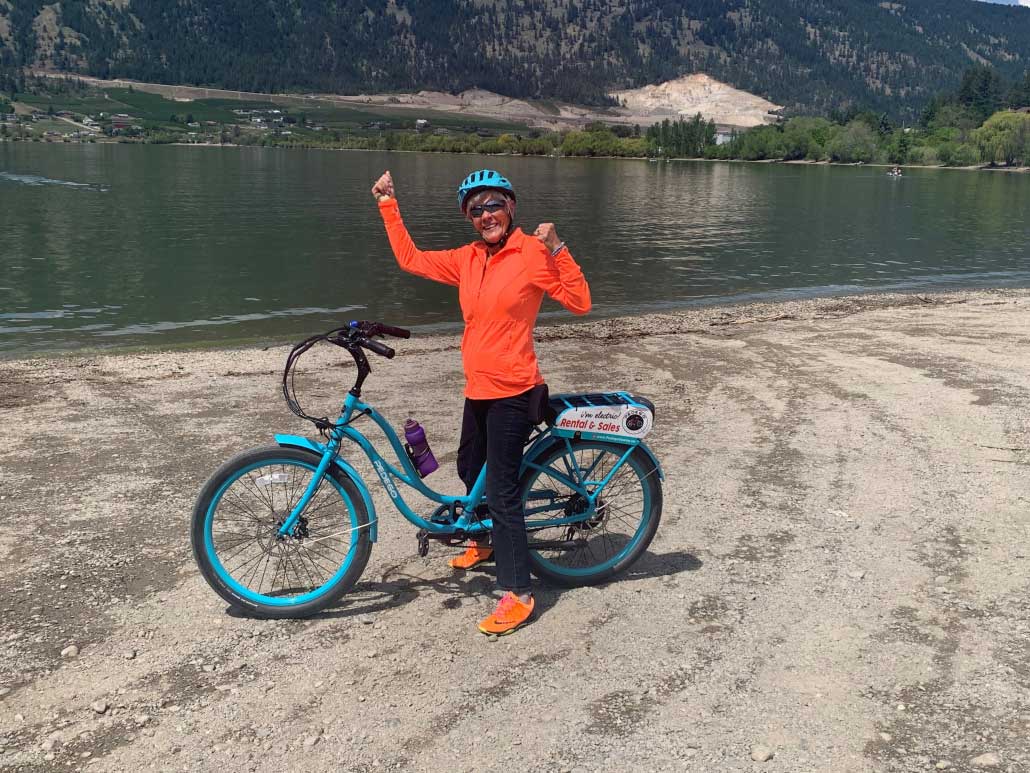 Woman celebrating ride to lake on teal coloured electric bike
