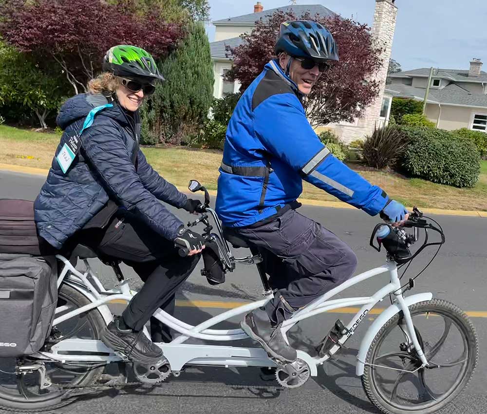 A couple rides their white Pedego tandem electric bike.