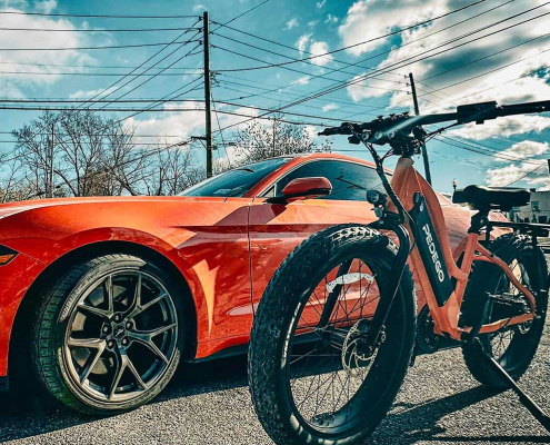 Orange car beside an orange Pedego Element ebike. Pedego eBike vs Electric Vehicle