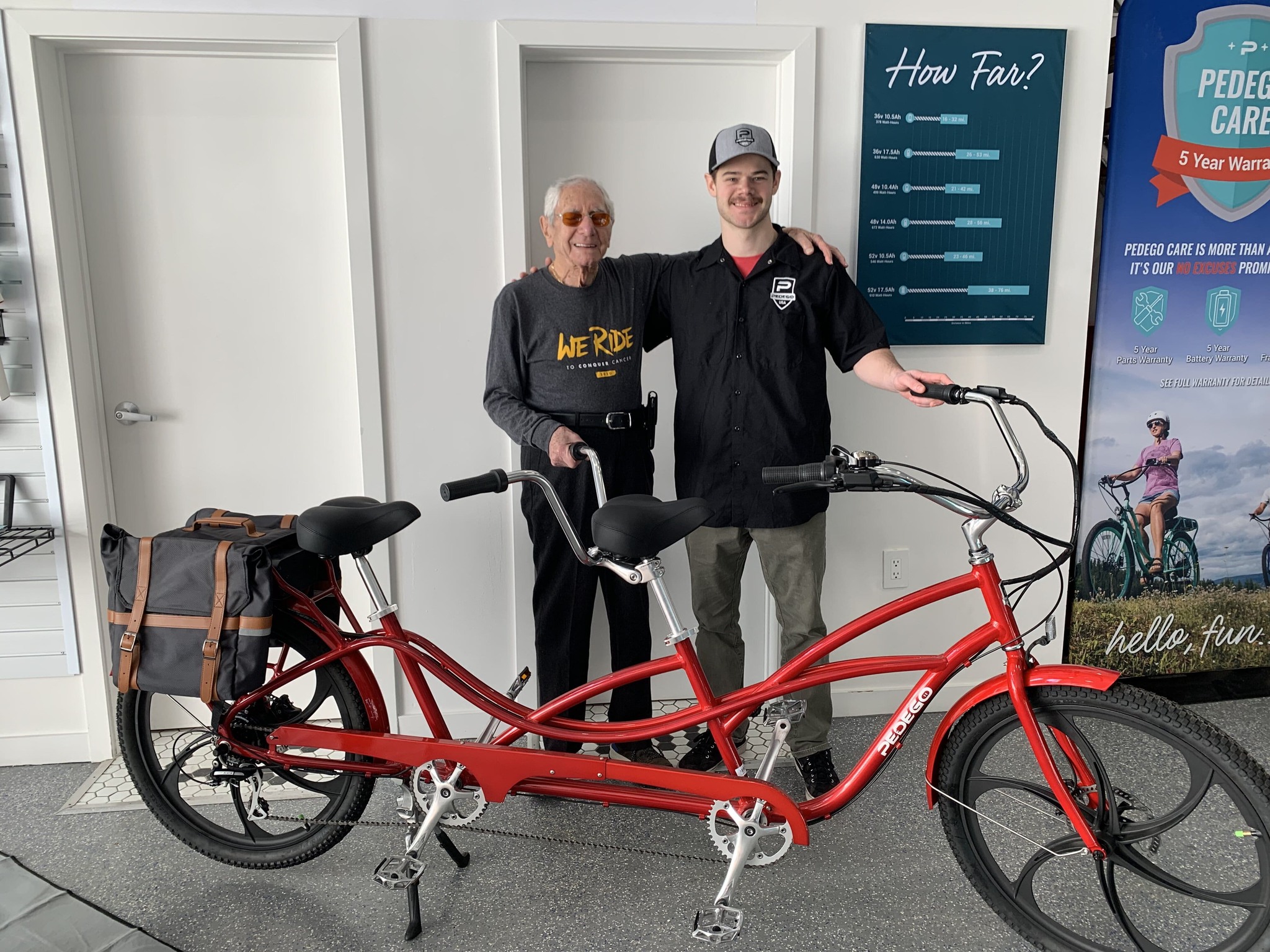 Two men stand with a Pedego Tandem inside Pedego Toronto store.