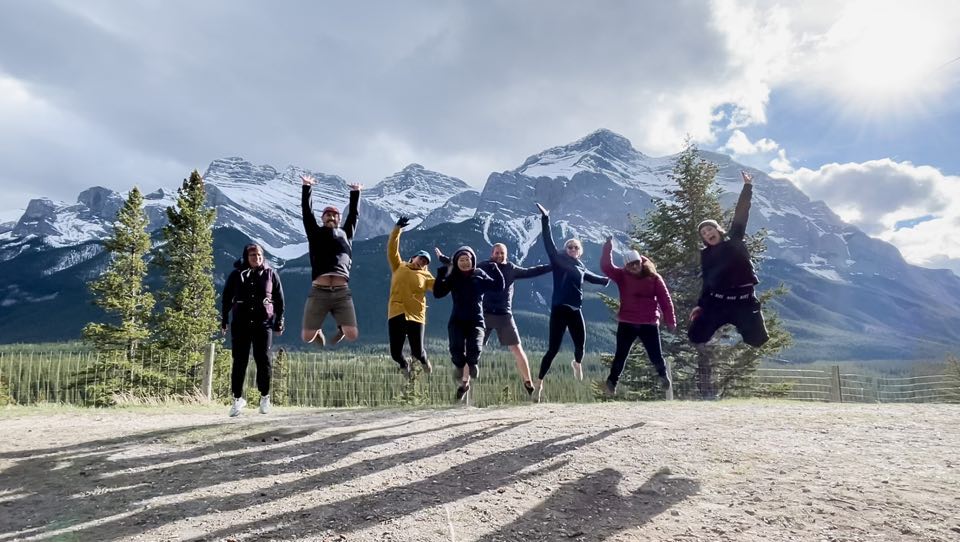 A group of people jumping in celebration with rocky mountains in the background