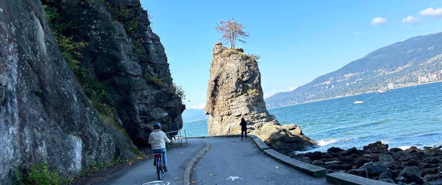 Person riding a pedego ebike on the seawall in Vancouver with the ocean in the background