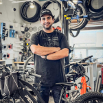 Shop lead at Pedego Canmore store stands in mechanic space with Pedego ebike.